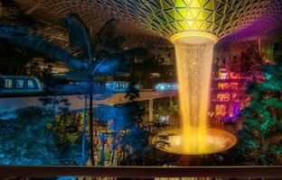 joya Changi aeropuerto lluvia vórtice, el mas grande interior cascada en el mundo y el habitación central de joya Changi aeropuerto por noche foto