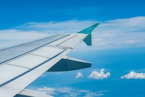 Clear blue sky with fluffy ornamental cumulus clouds, panoramic view from an airplane, wing close-up. Dreamlike cloudscape. Travel, tourism, vacations, weekend, freedom, peace, hope, heaven concepts photo