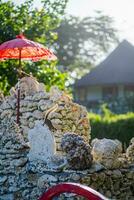 Squirrel jumping at traditional balinese umbrella and rock wall on the beach of Kuta Bali photo