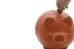 child hand putting coin into piggy bank from the top view isolated on white background, saving concept. Copy space for your text photo