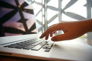 Working by using a laptop computer on wooden table. Hands typing on a keyboard. photo