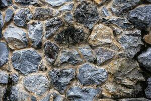 Dark masonry wall texture. Black stones and rocks of different shape, gray background photo