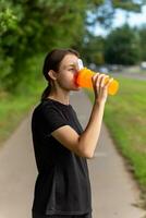 Fit tennage girl runner outdoors holding water bottle. photo