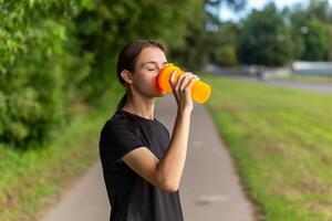 Fit tennage girl runner outdoors holding water bottle. photo