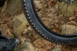 Detail of a mountain bike tire with a slightly muddy sidewall standing on a rocky surface. photo