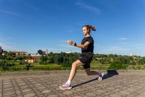 Young, fit and sporty girl in black clothes stretching after the workout in the urban city park. photo