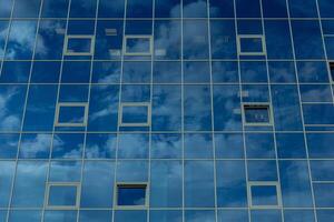 Architectural detail of the facade with multiple reflections of cloudy sky and the sun. photo