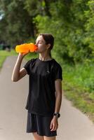 Fit tennage girl runner outdoors holding water bottle. photo