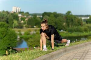 joven, ajuste y deportivo niña en negro ropa extensión después el rutina de ejercicio en el urbano ciudad parque. foto