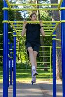 Portrait of beautiful teen age athletic girl training outdoors at open air gym at summer sunny day photo