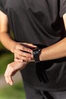 Teenage girl in black clothes checking her fitness watch after a workout. photo