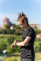 Teenage girl in black clothes checking her fitness watch after a workout. photo