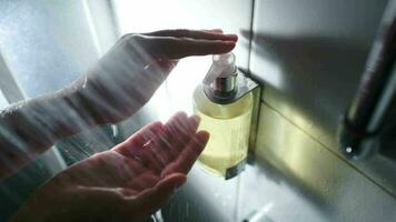 Female hands pushing container with liquid soap while taking a shower video