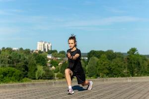 Young, fit and sporty girl in black clothes stretching after the workout in the urban city park. photo