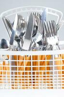 a white dish rack with orange and silver utensils photo