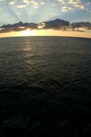 a boat is sailing across the ocean at sunset photo