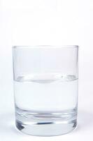 a glass of water sitting on a white surface photo