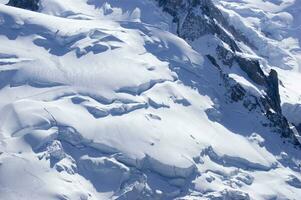 two people are hiking up a mountain with snow covered mountains photo