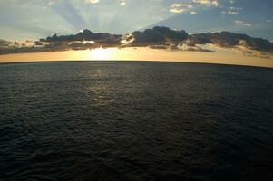 un barco es navegación a través de el Oceano a puesta de sol foto