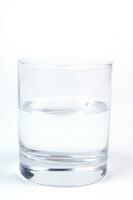 a glass of water sitting on a white surface photo