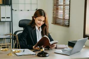mujer abogado leyendo legal libro con mazo en mesa en oficina. justicia y ley ,abogado concepto. foto