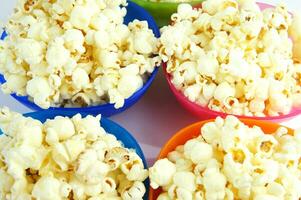 four colorful bowls of popcorn on a white surface photo