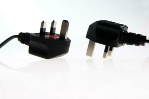 two black plugs with one plugged into the wall photo