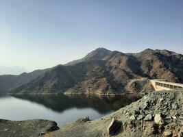 un hermosa tiempo de día ver de cauce qanuna represa en Alabama bah, saudi arabia el agua de el represa y el rodeando colinas son presentación un hermosa escena en el luz de sol. foto