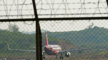 phuket, Thailand februari 10, 2023 - luchtbus a320, hsbbw van luchtazië vertrek Bij phuket luchthaven. visie door de luchthaven schutting, vlak te hard rijden omhoog voor uittrekken video