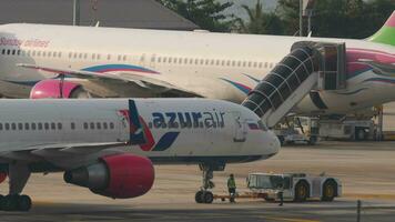 PHUKET, THAILAND FEBRUARY 26, 2023 - Towing an airliner. Boeing 7572Q8, RA73071 of Azur Air at Phuket Airport. Flight getting ready to take off. Aircraft preflight maintenance video