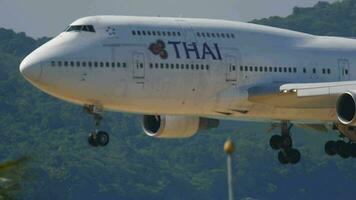 PHUKET, THAILAND NOVEMBER 26, 2016 - Widebody aircraft Boeing 747 of Thai Airways landing at Phuket airport. Jumbo jet passenger flies, side view. Tourism and travel concept video