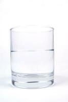 a glass of water sitting on a white surface photo