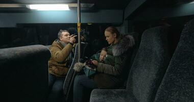mamá y hijo utilizando móvil en el autobús, padre tomando vídeo de ellos video