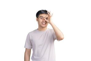 Young handsome elegant man wearing blue t-shirt over isolated background with happy face smiling doing ok sign with hand on eye looking through fingers photo