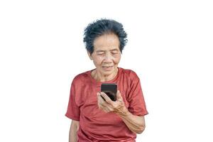 Asian senior woman smiles and video call isolated in white background. Strong elderly grandmother feeling happy using mobile cell phone to communicate with family and enjoy retirement life in house. photo