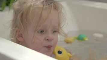 poco ragazza giocando con giocattoli nel il bagno video