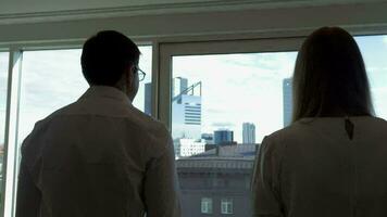 Two businesspeople go to window in the office video