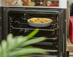 Cherry pie is baked in an electric oven in home kitchen photo