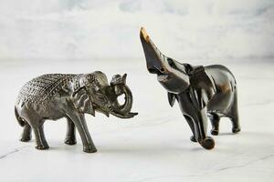 Figurines of elephants made of wood on white marble photo