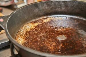 Caramelized syrup in frying pan on gas stove photo