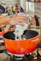 Chef puts chopped onions into a pot on gas stove photo