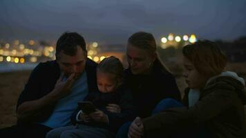 familie aan het kijken scherm Aan oceaan strand video