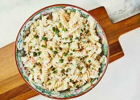 Fusilli salad with shrimp and green onions in colored bowl photo