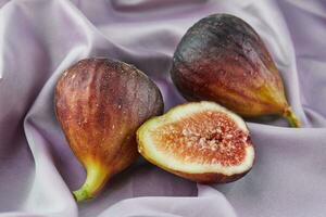 Whole fig and half lie on purple silk photo