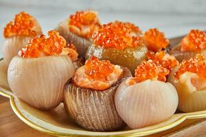 Shallots stuffed with meat and red caviar on plate photo