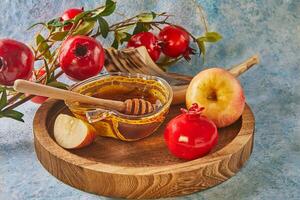 Rosh hashanah - jewish new year holiday concept. Bowl in the shape of an apple with honey, apples, pomegranates, shofar on a blue background photo