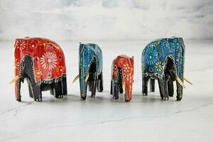 Elephant figurines of different colors and shapes on white marble photo