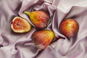 Whole fig and half lie on purple silk photo