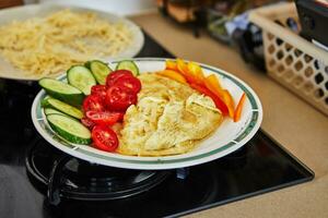 Mañana sano desayuno de revuelto huevos con parmesano queso, pepinos, Cereza Tomates y campana pimientos en hogar cocina foto