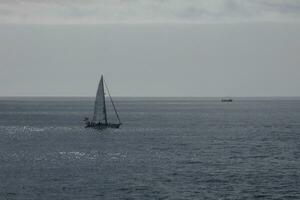 velero con vela desplegado, navegación en el calma mar a puesta de sol. foto